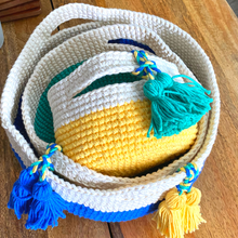 Load image into Gallery viewer, A set of three baskets crocheted from Cascade Yarns Nifty Cotton in Yellow, Green and Blue are shown, sitting in a stack.
