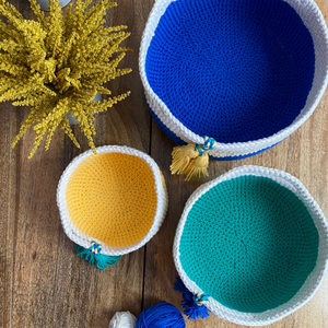 A set of three baskets crocheted from Cascade Yarns Nifty Cotton in Blue, Green and Yellow with Natural color handles are shown.
