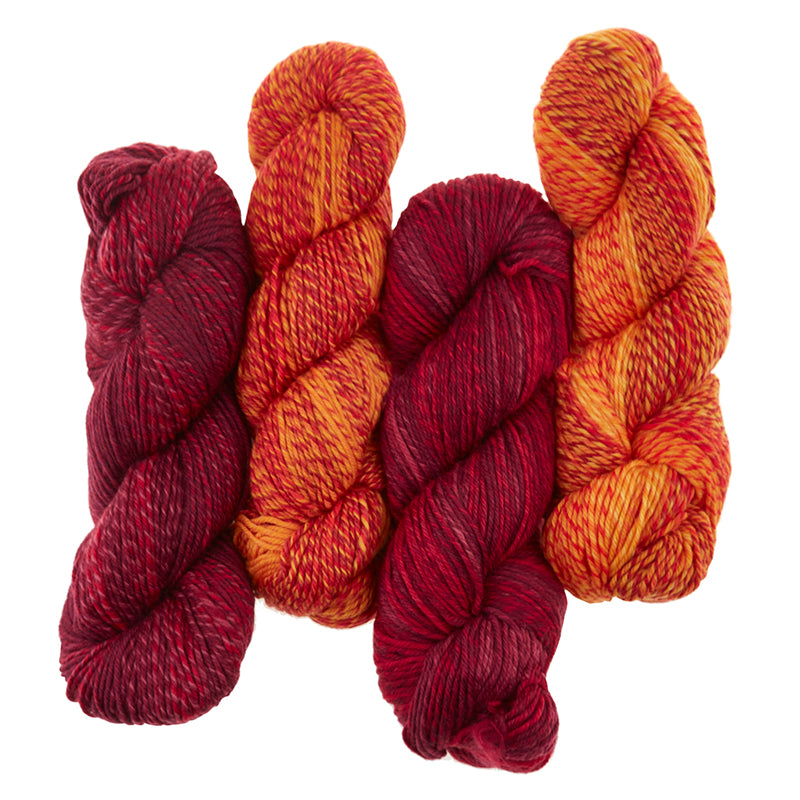 4 skeins of Cascade 220 Superwash Wave are shown in Solar (Orange) and Roses (red). The yarn is plied and has a long fading effect.
