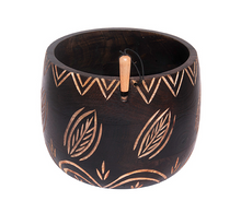 Load image into Gallery viewer, A wooden yarn bowl is shown in black with etched leaf designs that allow the natural wood color to show through.
