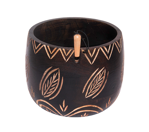 A wooden yarn bowl is shown in black with etched leaf designs that allow the natural wood color to show through.