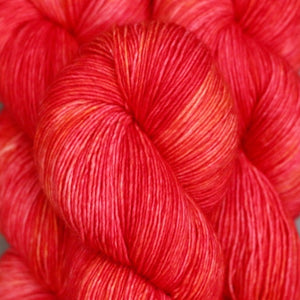 Skein of Madelinetosh Tosh Sock Sock weight yarn in the color Pop (Red) for knitting and crocheting.