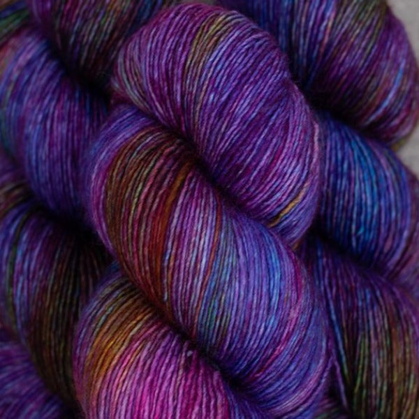 Skein of Madelinetosh Tosh Vintage Worsted weight yarn in the color Spectrum (Purple) for knitting and crocheting.
