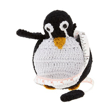 Load image into Gallery viewer, A crochet covered tape measure in the shape of a black and white penquin with a yellow beak and feet.

